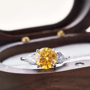 Macro shot of a classic three-stone ring with yellow round center gem and side pear diamonds