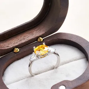 Macro detail of a 3 carat yellow moissanite ring with pear side stones in a wooden box