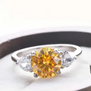 Macro shot of yellow round diamond ring with pear-shaped side stones in silver setting