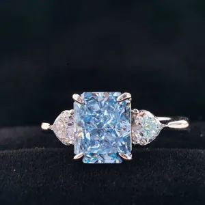 Macro detail of radiant cut blue gem stone with pear shaped side diamonds in silver claw setting