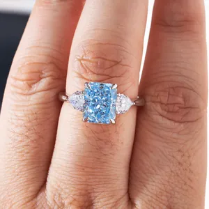 Macro detail of radiant cut light blue gemstone ring with pear side stones on hand