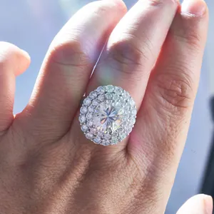 Gros plan d'une bague en moissanite ovale avec double halo portée au doigt sous la lumière