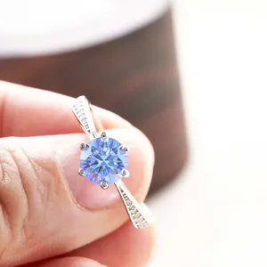 Close-up of a blue moissanite ring in a six-prong setting with side diamond accents