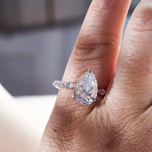 Vista detallada de un anillo moissanita de 4 quilates en forma de pera en la mano