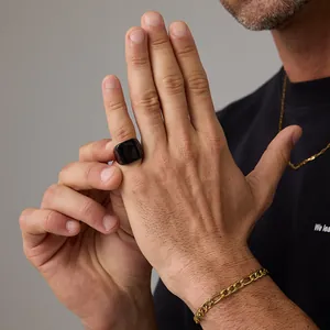 Close-up of a polished black signet ring paired with golden link chains on a male model