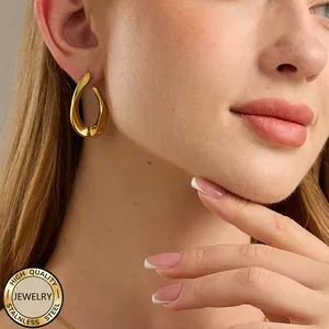 Close-up of golden irregular drop earring on model made of polished stainless steel
