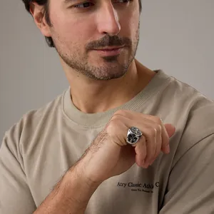 Détail macro d'une bague chevalière vintage en acier pour homme avec croix gravée sur main
