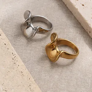 Detailed close-up of wavy 18K gold and silver stainless steel rings on a stone base