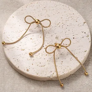 Detailed view of gold bow-knot tassel earrings with snake chain and metallic beads
