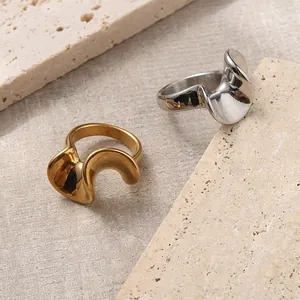 Artistic 18K gold and silver plated wavy stainless steel rings on a natural stone base