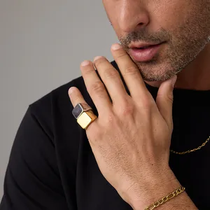 Close-up of gold and silver square signet rings worn with a Figaro bracelet