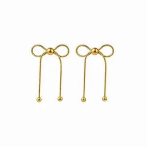 Golden bowknot earrings with long metal tassels and bead drops in a minimalist style