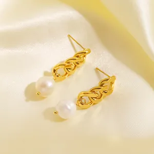 Détail de boucles d'oreilles pendantes à chaîne dorée avec perles sur fond en soie