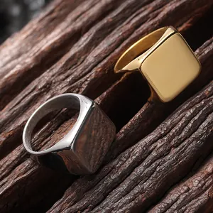 Close-up of square signet rings in gold and silver finish on rustic wooden texture