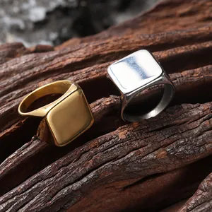 Close-up of polished gold and silver square signet rings on dark wood background