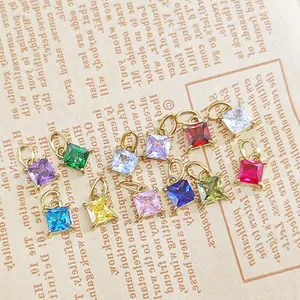 Macro shot of twelve colorful square-cut gemstone charms with golden claw settings