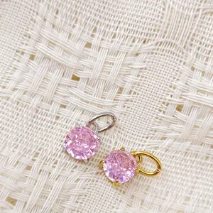 Makroaufnahme von 18K gold- und silberplattierten rosa Zirkon-Anhängern auf Stoff