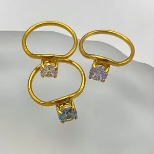 Dettaglio macro di tre anelli a onda placcati in oro 18K con grandi zirconi a taglio tondo