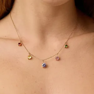 Detail of elegant gold necklace with five colorful round gemstones on a model's neck