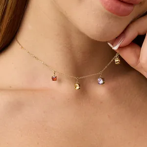 Close-up of four-claw set colored gemstone pendants on a gold chain necklace for women