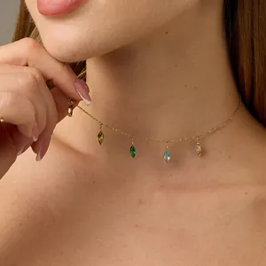 Nahaufnahme einer goldenen Halskette mit fünf bunten Zirkonia-Anhängern am Hals