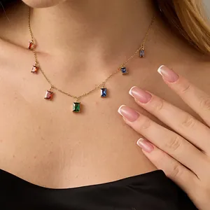 Detail of gold rectangular multi-color zirconia charms hanging on a dainty fine chain