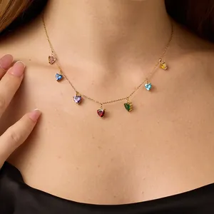 Detail shot of a model wearing a gold necklace featuring seven colorful heart-shaped zircons