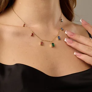 Close-up of gold necklace with rectangular colorful gemstones worn by a model