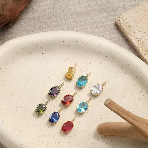 Lot de dix pendentifs ovales en zircon coloré sertis griffes dorées sur plateau en céramique