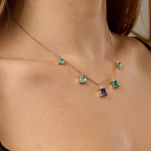 Close-up of golden necklace with five gradient blue rectangular gemstones on model