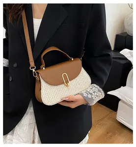 Detail view of woven straw and brown leather patchwork bag with gold buckle hardware