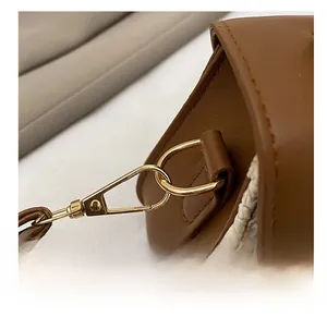 Detailed macro view of premium gold D-ring and lobster clasp on a straw handbag