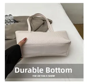Detail view of the wear-resistant reinforced bottom of this cream faux leather tote bag