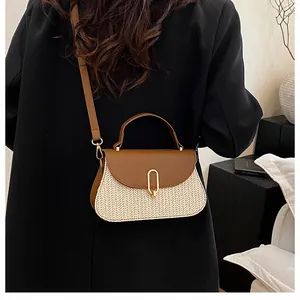 Close-up of beige straw and brown leather shoulder bag shown on a model's arm
