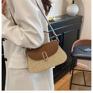 Detail of a chic straw woven bag with brown leather flap and golden oval metal lock