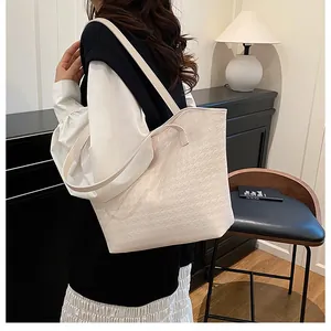 Detail of cream woven tote bag featuring geometric texture and elegant shoulder strap