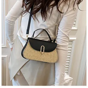 Detail of woven straw handbag with black leather flap and gold oval buckle on model