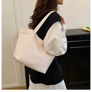 Detail of large beige houndstooth woven tote bag on shoulder for daily commute