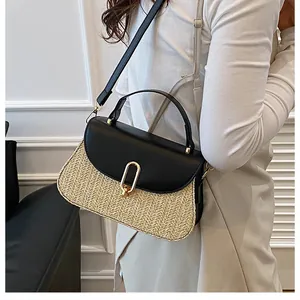 Detail of a straw patchwork handbag with black leather flap and gold clasp on a model