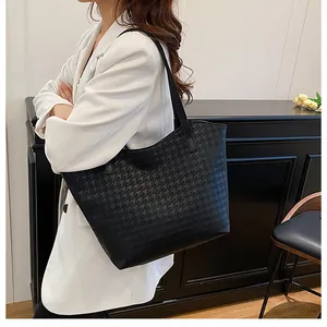 Detail of black large tote bag with star textured embossing on a model in white blazer