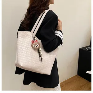 Detailed view of white houndstooth pattern tote bag with a soft plush bear charm
