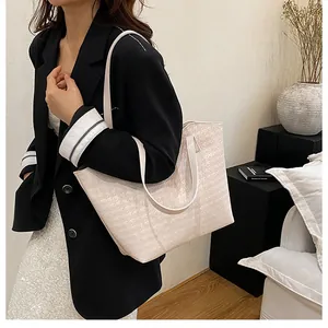 Close-up of large beige woven tote bag with houndstooth texture and elegant long handles