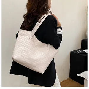 Detail of large beige tote bag with textured houndstooth pattern worn on shoulder