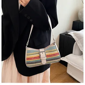 Détail du sac en paille arc-en-ciel avec bandoulière en cuir blanc et boucle argentée