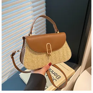Detail of straw woven bag with brown leather trim and golden U-shaped metal buckle