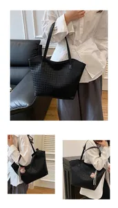 Detail of black houndstooth embossed tote bag featuring a cute beige plush bear charm
