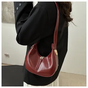 Close-up of red patent leather crescent hobo bag with gold hardware worn by model