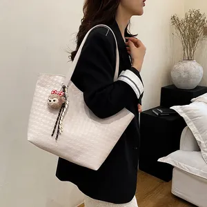 Chic beige houndstooth tote bag with large capacity and plush charm shown on a model