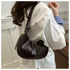 Detailed side view of a dark brown glossy hobo bag with sleek gold hardware accents