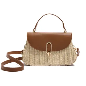 Stylish woven straw handbag with brown leather trim and golden oval metal buckle